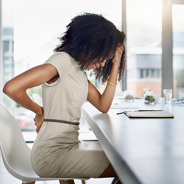 woman in an office holding her lower back in pain